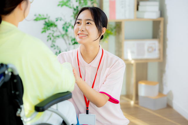 車椅子の女性と会話する介護士