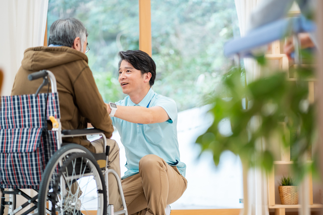 車椅子の高齢男性に話しかける介護士