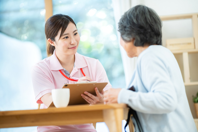 介護士が高齢女性と話しながらメモをとる