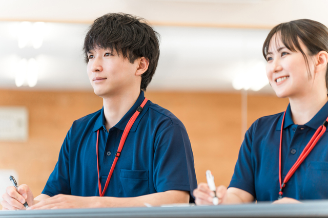 制服を着て着席し前を向く男女