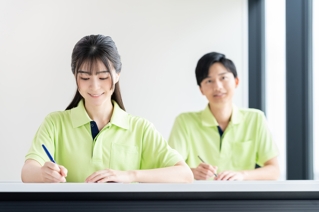 制服を着て机に座りペンを持つ男女
