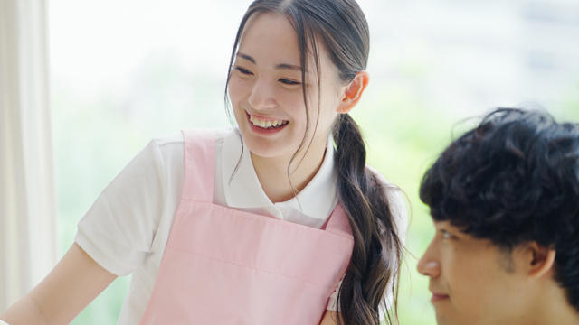 エプロンをした女性が男性と話す